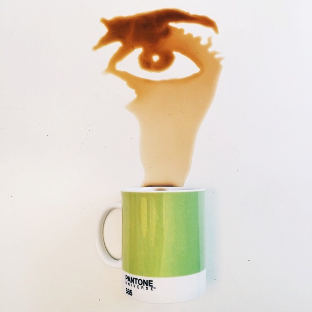 A whimsical play of coffee and creativity capturing a silhouette of an eye formed by coffee spill above a Pantone mug.