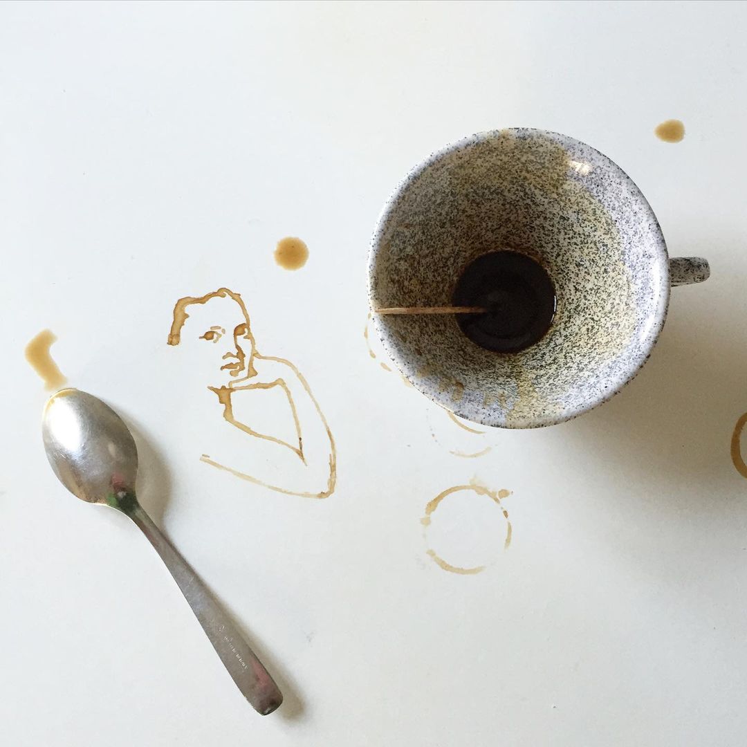 A creative display of coffee cup stains depicting a person's face on a white surface.