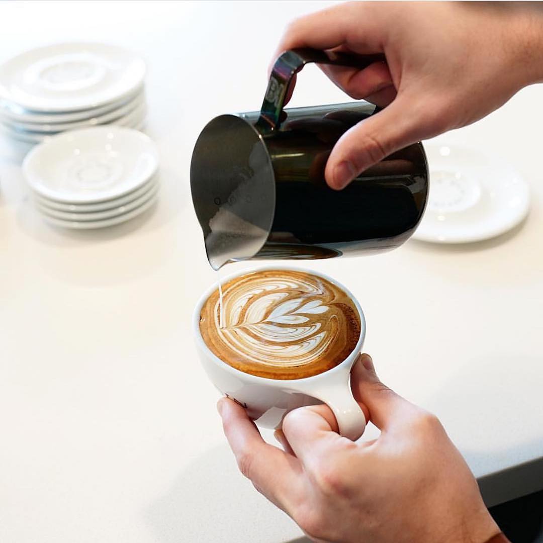 A barista crafting a latte with intricate latte art