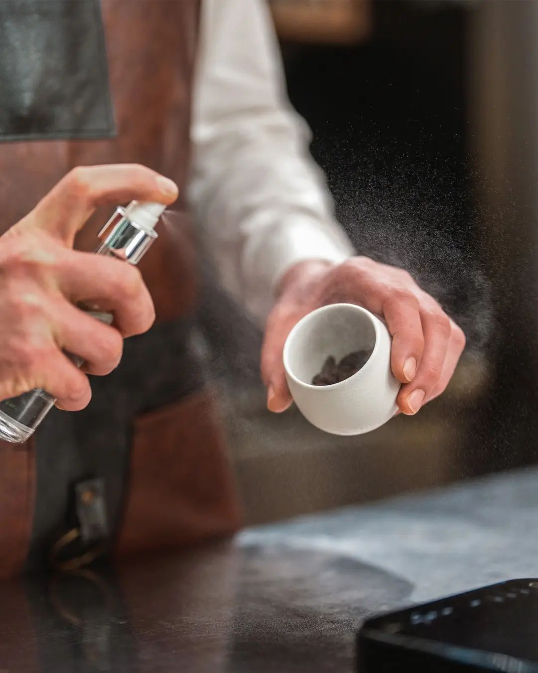 Person applying a fine spray of a substance onto a cup