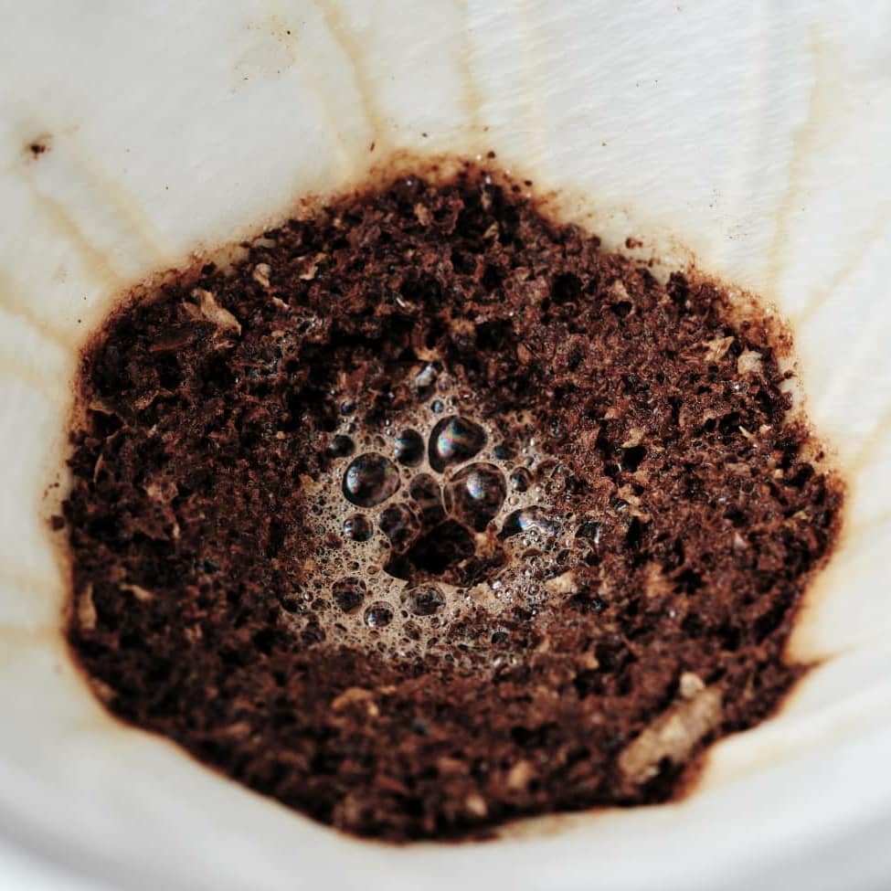 Close-up of used coffee grounds in a filter after brewing, showcasing the texture and bubbles