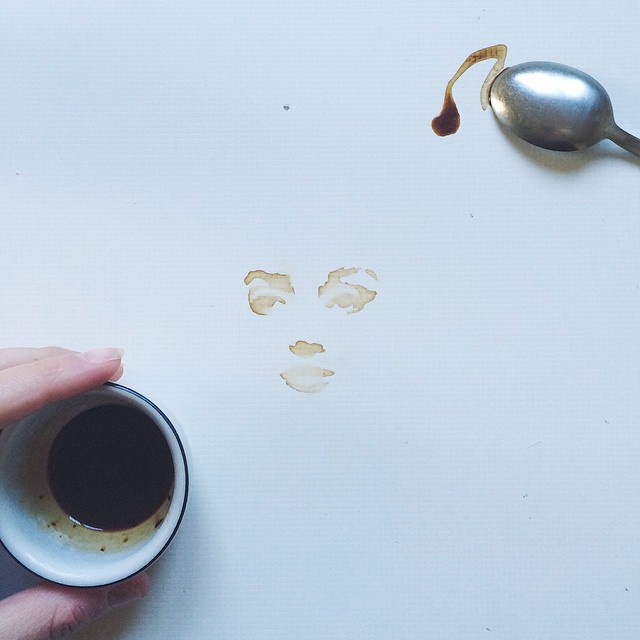 A whimsical composition with a spilt coffee creating a face next to a spoon