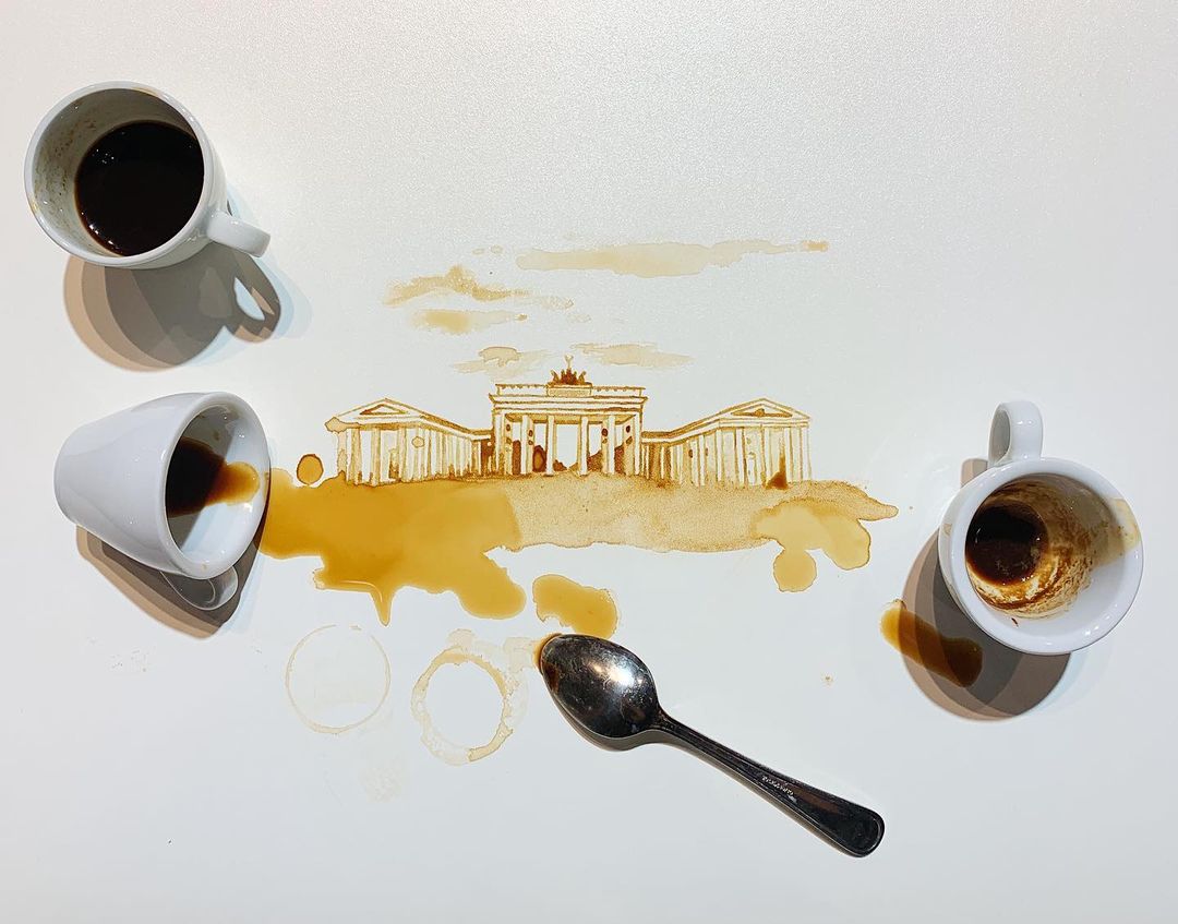 An inventive artwork utilizes spilled coffee to paint the Brandenburg Gate