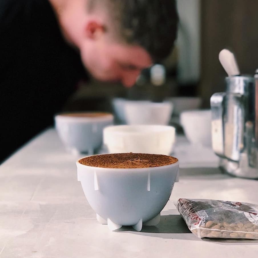 A person meticulously evaluating coffee quality during a cupping session