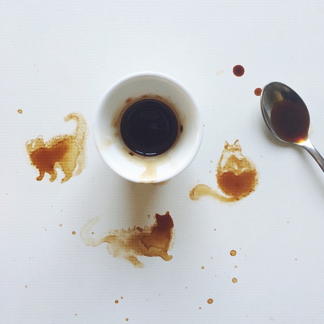 Abstract coffee stains forming cat shapes on a white surface.