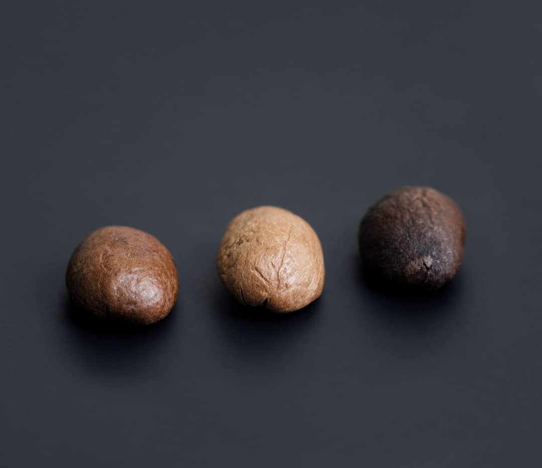 Three different stages of roasted coffee beans on a dark background