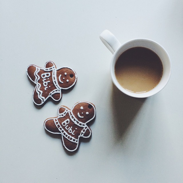 Two gingerbread cookies next to a cup of coffee