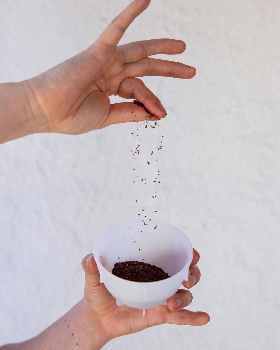 Hand pouring ground coffee