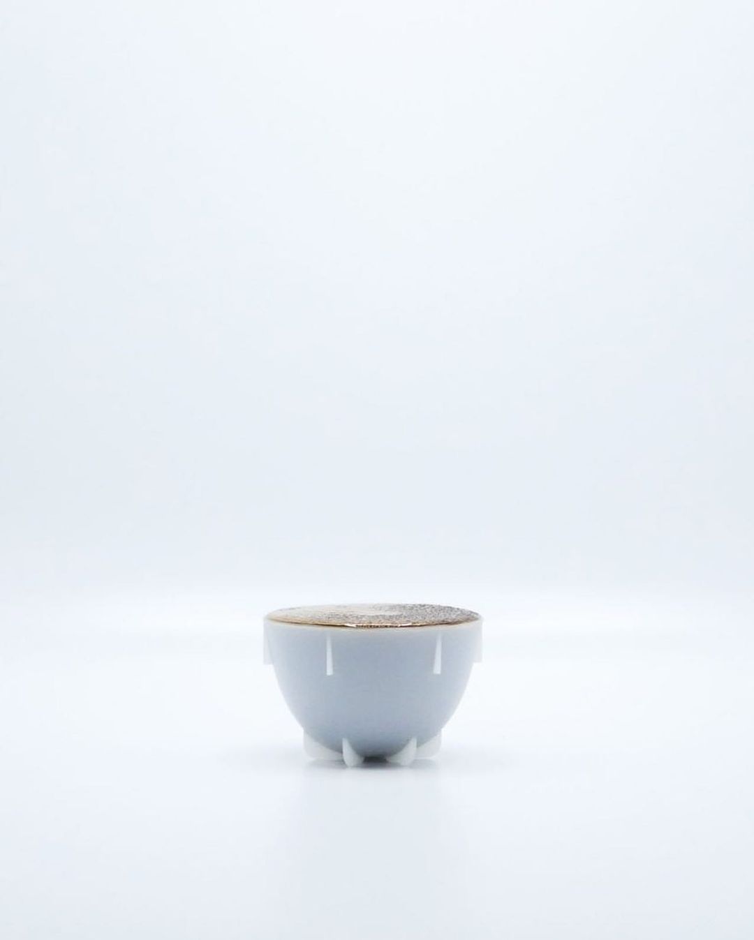 A minimalist white bowl filled with a frothy beverage on a pure white background