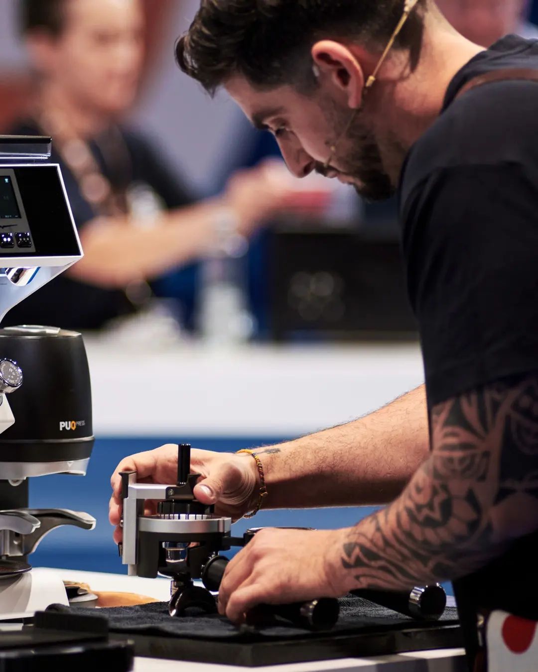 A focused individual with tattoos carefully calibrates an advanced espresso machine